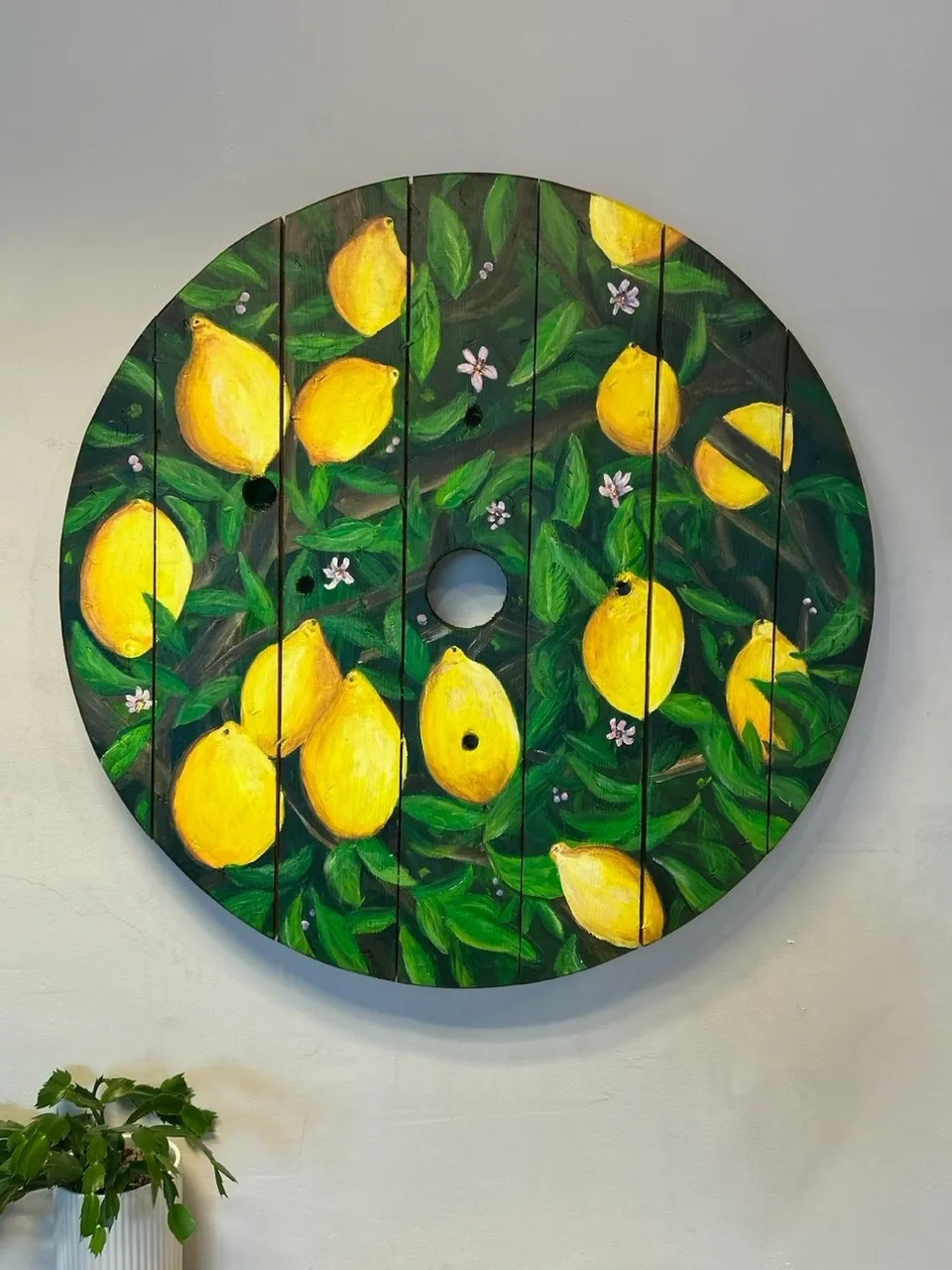 Gule citroner hænger mellem mørkegrønne blade og små hvide blomster; til højre er en citron skåret over.