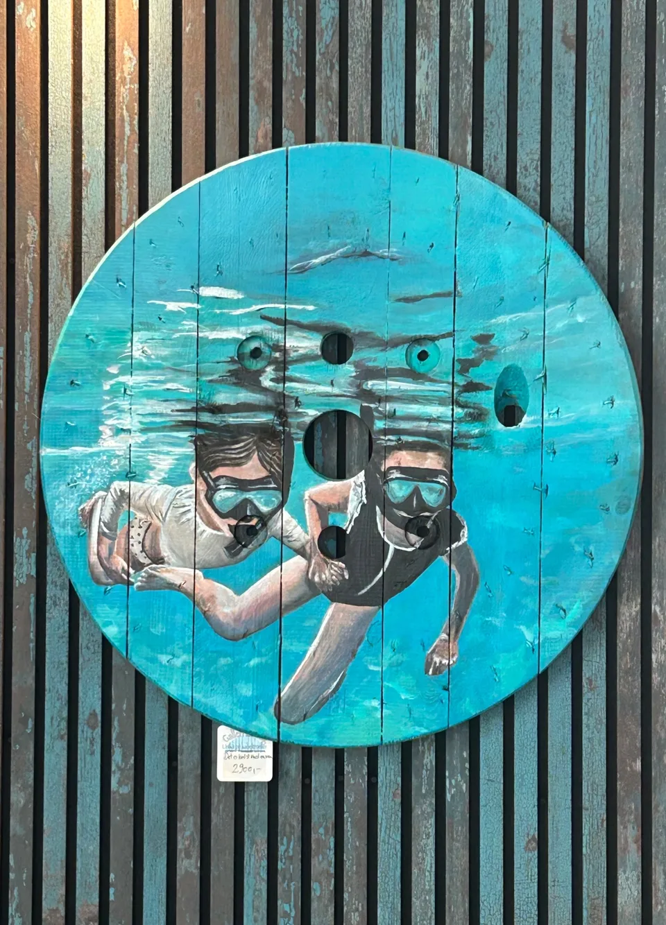 To børn med dykkermaske og snorkel svømmer side om side under vandet i turkisblåt vand med overfladen glitrende over dem.